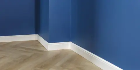Un coin de pièce aux murs bleu profond, avec un parquet imitation bois clair et un élégant type de plinthe blanc.