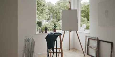 Ljust rum med staffli, tom duk, växter och rullar med papper. Perfekt rum inspo för en konstnär.