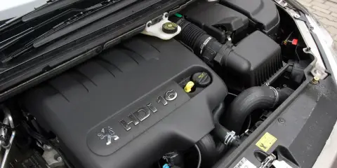 Silnik 2.0 HDI pod czarną osłoną z logo Peugeot. Widać przewody, filtr powietrza i zbiorniczek płynu.
