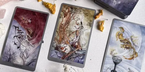 Trzy karty tarota: Dziesiątka Mieczy, Królowa Buław i As Kielichów, tworzą magiczną atmosferę. Idealne do wróżenia, jak tarot online, który się sprawdza.