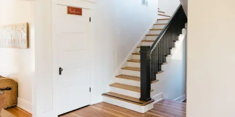 Escalier avec rampe noire, une idée couleur pour une cage d'escalier moderne. Une porte blanche avec un panneau "Restroom" est visible.