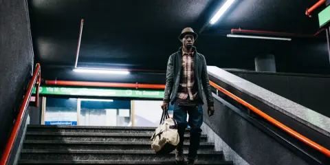 Uomo con borsa scende le scale di una metropolitana, un'immagine con un'atmosfera urbana e moderna. Queste foto creative catturano momenti di vita quotidiana.