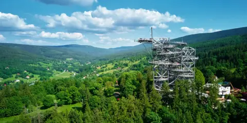 Wieża widokowa w Karkonoszach góruje nad zielonymi dolinami i małymi miasteczkami.