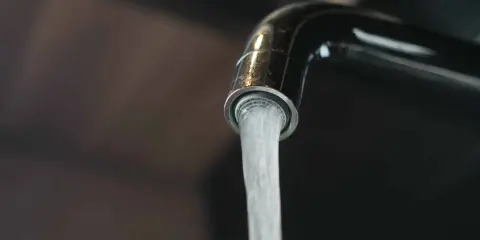 Un robinet chromé verse un jet d'eau. L'image évoque la dureté de l'eau par commune en France, un sujet important pour la vie quotidienne.