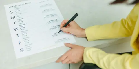 Planowanie posiłków na tydzień, w tym menu na weekendowe grillowanie. Kobieta zaznacza wypite szklanki wody.