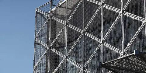Struttura geometrica di un edificio moderno con pannelli a rete metallica, esempio di materiali da costruzione innovativi.