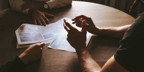 Intensywne spotkanie z klientem. Dłonie wskazują na dokumenty, omawiając szczegóły projektu.