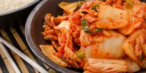 Miseczka z kimchi, obok ryżu i pałeczek.