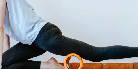 Frau in Sportkleidung dehnt sich mit einem Faszienroller.