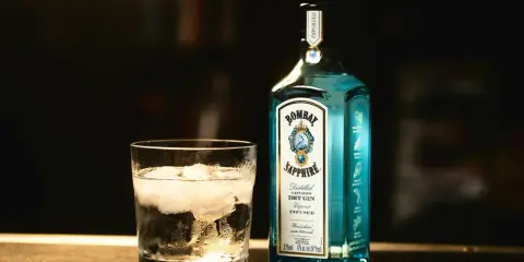 Szklanka z lodem i butelka Bombay Sapphire gin. Idealny składnik na orzeźwiający bombay sapphire drink.