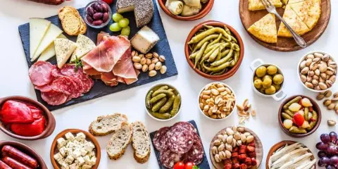 Un festin de tapas pour une pendaison de crémaillère : charcuterie, fromages, olives, cornichons, fruits secs et pain.