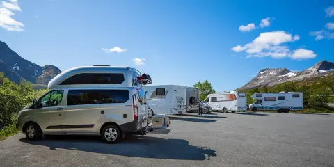 Flera husbilar står parkerade med en fantastisk bergig bakgrund. Drömmen om en husbil till Lofoten blir verklighet här.