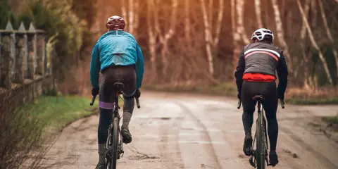 Dwóch rowerzystów w jesiennych strojach, idealnych na 15 stopni. Lekkie kurtki i długie spodnie zapewniają komfort podczas jazdy.