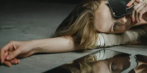 Une femme regarde des éclats de miroir, se demandant : "Suis-je narcissique ?" Son reflet brisé pose la question.