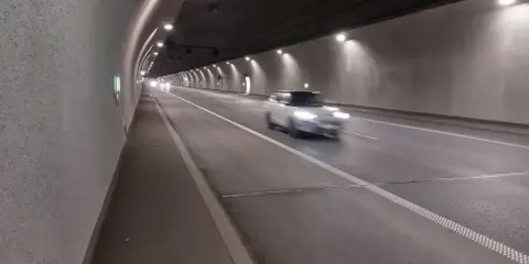 Biały samochód mknie przez oświetlony tunel w Zakopanem.