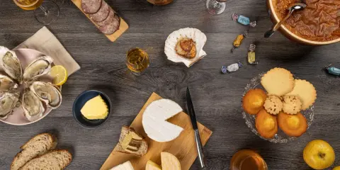 Un festin normand : huîtres, fromages, charcuterie, pommes et douceurs, accompagnés de verres de Calvados, pour savourer les spécialités locales.