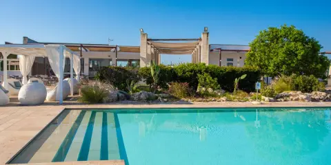 Piscina cristallina e lettini bianchi al le cesine resort, sotto un cielo azzurro. Relax e natura.