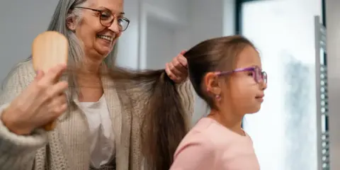 Babcia czesze wnuczkę, a jej siwe włosy przypominają o tym, dlaczego wypadają włosy.