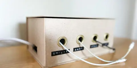 Kreative ladekabel aufbewahrung selber machen aus einem Karton. Kabel sind ordentlich durch Ösen geführt und beschriftet.