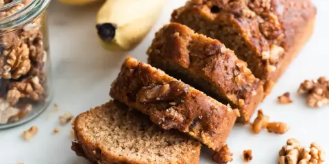 Tranches de délicieux dessert banane et noix, avec des bananes et des noix à proximité.