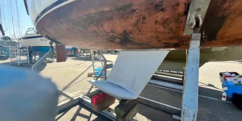 Vue du dessous d'un voilier sur bers. Le safran est visible, prêt pour l'étape 22 de la fiche technique.