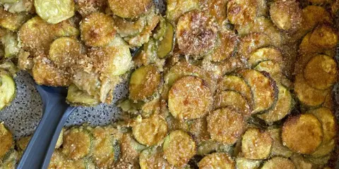 Fette di zucchine al forno dorate e croccanti, condite con parmigiano e pangrattato. Un contorno delizioso e facile da preparare.