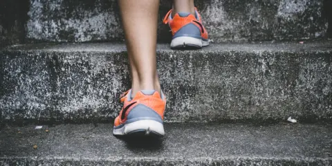Pomarańczowe buty sportowe na siłownię, idealne na trening, wspinają się po betonowych schodach.