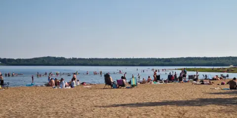 Folk njuter av solen och badar vid en strand, en perfekt plats för camping i Luleå.
