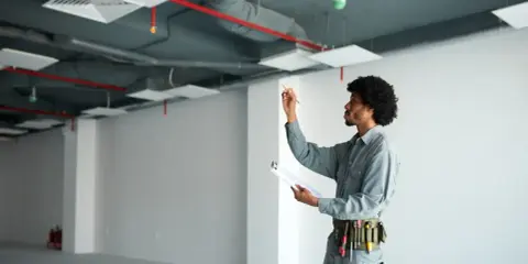Técnico revisa instalaciones en un local vacío, asegurando el cumplimiento de la normativa trasteros en garajes.