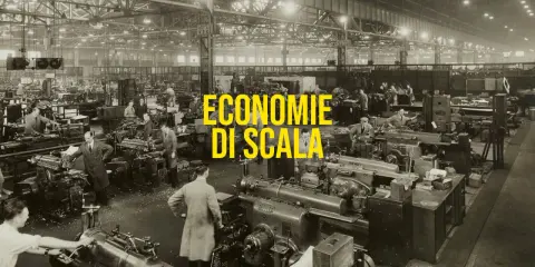 Operai in una grande fabbrica lavorano a macchine utensili, un esempio di economie di scala nella produzione industriale.