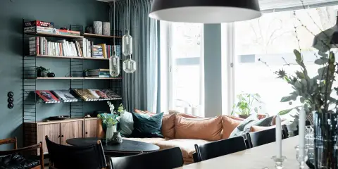 Vardagsrum med bokhylla i 50-talsstil, soffa i läder och stora fönster.