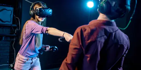 Para grająca w gry na Google VR, zanurzona w wirtualnej rzeczywistości, z kontrolerami w dłoniach.