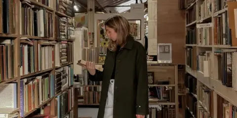 Kobieta w antykwariacie przegląda książki psychologiczne, które zmieniają życie. Wśród regałów pełnych literatury szuka inspiracji.