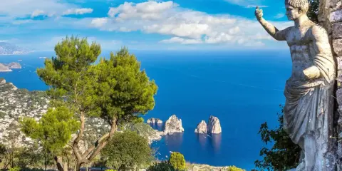 Statua antica guarda il mare blu intenso e i Faraglioni, icona dell'isola vicino Capri.