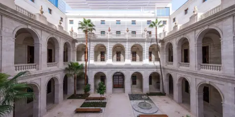 Hof des Malaga Museums mit Arkaden, Palmen und einem Brunnen.