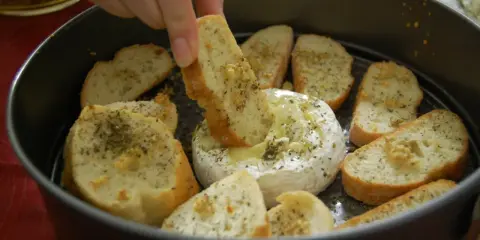 Ciepły, rozpływający się camembert z piekarnika, idealny do maczania w nim chrupiących grzanek z ziołami.