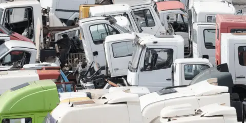 Desguace de camiones. Se aprecian cabinas blancas y verdes, algunas con partes oxidadas, listas para cumplir los requisitos de achatarramiento de camiones.