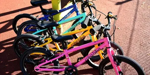 Rowerki dziecięce roko bikes w kolorach: różowym, żółtym, turkusowym i niebieskim, gotowe do zabawy na placu.