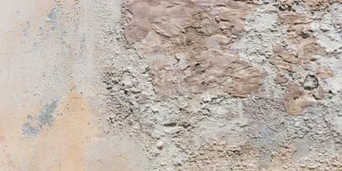 Texture d'un vieux mur dégradé, révélant des traces de salpêtre et des couches de peinture écaillée.