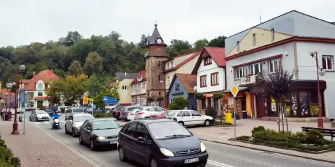 Tłoczny dobczyce rynek z wieżą zegarową, samochodami i skuterem.