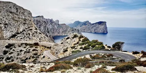 Carretera sinuosa en acantilados rocosos con vistas al mar azul. Un viaje en coche por un paisaje espectacular.