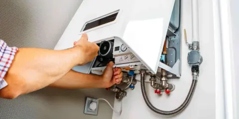 Man checks a gas boiler that won't ignite. He opens the cover to inspect the internal components.