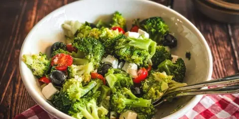 Frischer Brokkolisalat mit Kirschtomaten, schwarzen Oliven und Feta. Perfekt für gesunde Brokkoli Rezepte.