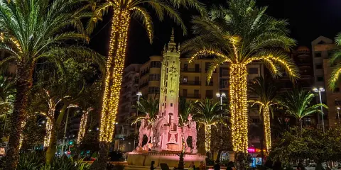 Nocna iluminacja palm i fontanny z rzeźbami. Wspaniała atmosfera, jakby trwały święta w Hiszpanii.