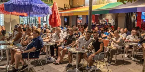 People enjoying drinks at outdoor tables outside gay bars in Sitges, Spain.