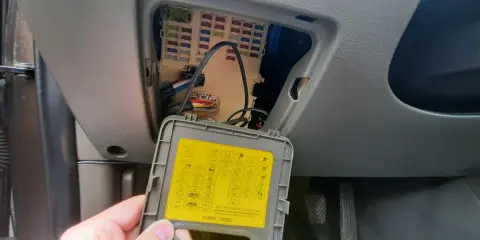 Wnętrze samochodu z otwartą skrzynką bezpieczników. Na klapce schemat, w tym oznaczenie dla navitel smart box max.