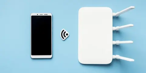 Biały router wifi z antenkami i smartfonem obok. Ikona sygnału wifi symbolizuje połączenie.