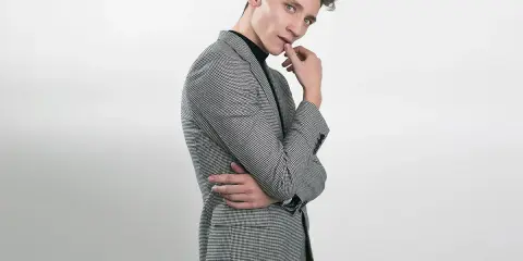 Elegancka stylizacja na 18 urodziny: młody mężczyzna w garniturze w drobną kratkę, czarny golf.