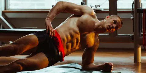 Mann macht seitliche Planke für Bauchtraining mit Hanteln.