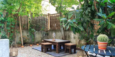 Un angolo relax per il tuo progetto giardino 50 mq: tavolino in legno intagliato, sgabelli, lanterne e un cactus vivace.